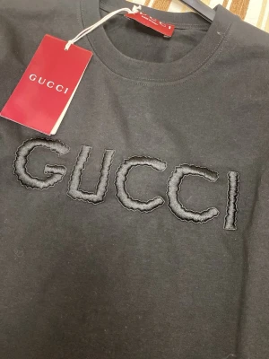 Svart t-shirt  - Svart t-shirt  Klassisk rund hals och korta ärmar. Tillverkad i mjuk bomull som känns skön mot huden. Perfekt för dig som vill ha en clean och lyxig look med tydlig designer-vibe.