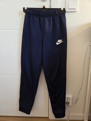 NIKE Byxor - Marinblåa NIKE byxor I premium skick.        Inga fickor❌️                                                    Hel logga✅️ Bekväma✅️ Sällan använda✅️ STORLEK: 147-158cm  Vid köp av 2 eller fler artiklar på min profil kan ordrarna skickas samma dag annars skickas ordern nästkommande dag. 