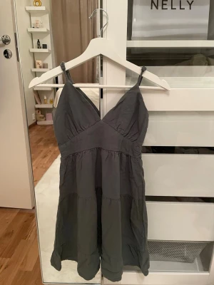 Grön miniklänning med smockad rygg med V-neck  - Säljer en mörkgrön sommar mini klänning med smala axelband och v-ringad överdel.     Har inte mer info än så eftersom den är köpt utomlands (los Angeles 