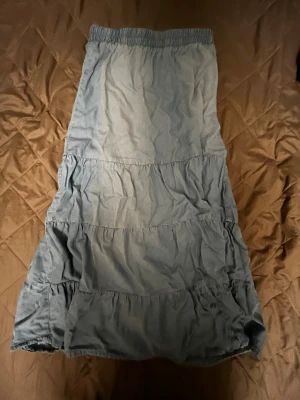 Ljusblå långkjol med volanger - Säljer en ljusblå långkjol med resår i midjan och flera volangdetaljer längs kjolen. Storlek 36 funkar som s🥰