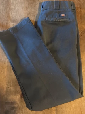 Grå Dickies 874 Original Fit byxor - Säljer ett par klassiska Dickies 874 Original Fit byxor i mörkgrå färg. Byxorna har rak passform, normal midja och är tillverkade i slitstarkt material med dragkedja och knapp framtill. 