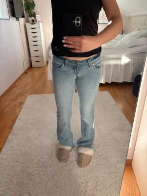 Ljusblå bootcut jeans med låg midja - Säljer ett par ljusblå jeans från Abrand som är bootcut och låg midja. De har ett pyttelitet hål på ena sidan av benet men synas knappt💕köpte för 1000kr! De är i tall men jag är ungefär 160cm så ja klippte av de