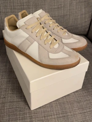 Maison Margiela sneakers (ÄKTA) - Maison Margiela gats i storleken 44 och i färgen vit/grå. Köpta i maj 2025 så det finns tecken på användning. 1. Fläck på tån på högra skon (visas i bild 1). 2. Lite sliten på sulan vid hälen (visas i bild 5). Ätkthetsbevis finns!✅. Allt orginalt följer med!✅. Jag är öppen för prisförslag!✅