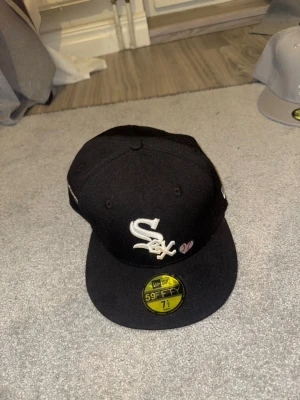 S New Era 59FIFTY White Sox Fitted Keps - Säljer en svart New Era 59FIFTY keps med White Sox-logga framtill och broderad text bak. Gittes Keps,Nyskick och aldrig använd 
