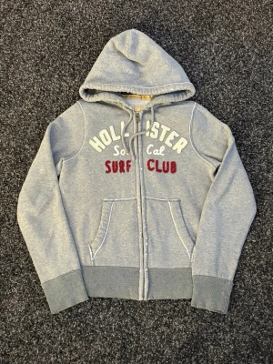 Hollsiter zip-sällsynt   - Säljer nu denna sjukt eftertraktade Hollister hoodie. Mycket fin hoodie i skick 9/10. Väldigt populär modell och perfekt för säsongen. (Sliten design)  • Perfekt till kyligare dagar • Skön passform, lätt att styla • Vintage / Y2K-inspirerad – sällsynt och eftertraktad • Passar både vardag och layering  📏 Storlek: S 📦 Skickas omgående 💬 Pris kan diskuteras vid snabb och smidig affär