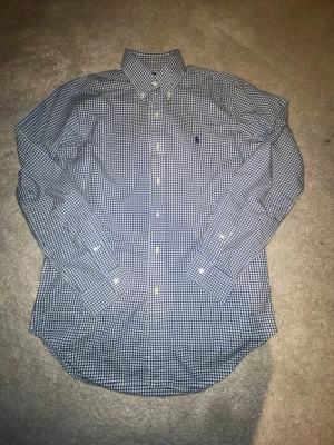Rutig skjorta från Ralph Lauren S - Säljer en klassisk rutig skjorta från Ralph Lauren i blått, grönt och vitt. Skjortan har lång ärm, knappar hela vägen och broderad logga på bröstet. Classic fit-modell i mjuk bomull, perfekt till jeans eller chinos.