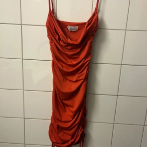 Röd klänning från Oh Polly - Säljer en snygg röd kortklänning från oh Polly med tunna axelband och draperad framsida. Klänningen har justerbara snören i sidorna. Har används 1 gång💕💕
