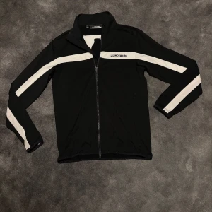 Svart fullzip från J.Lindeberg - Säljer en mycket snygg svart fullzip från j.lindeberg som är i mycket gott skick, den har inte används överdrivet mycket. Storlek M men passar även S! Hör av vid frågor👍🏻