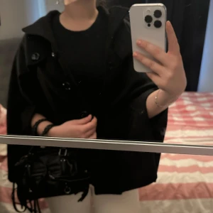 Svart poncho - Svart poncho med knappar och öppningar för armarna💕