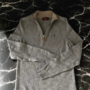 Grå merinoulltröja från Morris - Snygg grå långärmad tröja från Morris i 100% merinoull. Tröjan har half zip-dragkedja vid kragen och en liten broderad logga på bröstet. Perfekt för dig som gillar stilrena och bekväma plagg med premiumkänsla. Storlek M men passar S också