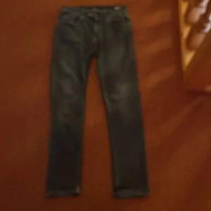 Replay jeans - Säljer ett par svarta jeans från Replay med klassisk femficksdesign och raka ben. Jeansen har snygga slitningar och detaljerade sömmar. Perfekta för dig som gillar en stilren och tidlös look.