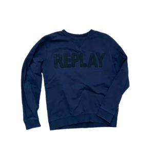 Mörkblå sweatshirt från Replay - Snygg mörkblå sweatshirt från Replay med stort REPLAY-tryck framtill. Tröjan har rund hals, långa ärmar och ribbade muddar vid ärmslut och nederkant. Tillverkad i mjuk bomull som är skön mot huden. Perfekt för dig som gillar stilrena och bekväma plagg.