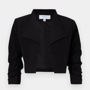 Svart croppad kavaj från Vila - Snygg svart croppad kavaj från Vila med breda slag och långa ärmar med rynkade detaljer. Perfekt för dig som vill ha en stilren och trendig look. Jackan har en klassisk kavajkrage och är tillverkad i ett mjukt material.
