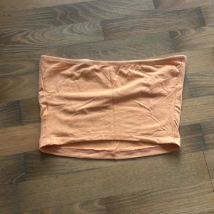 Orange tubtopp från SHEIN - Säljer en enkel orange tubtopp från SHEIN. Toppen är bandeau-modell, ärmlös och tillverkad i mjuk bomullsmix. Perfekt för varma dagar och enkel att matcha med jeans eller kjol. Det står inte storlek då jag köpte second hand men skulle uppskatta runt S.