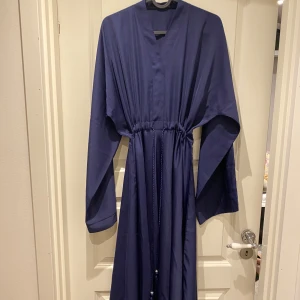 Marinblå abaya med snörning - Mörkblå abaya, köpt i Dubai. Använd vid 2 korta tillfällen. Som ny. Passar alla storlekar då den har band i mitten och kan justeras