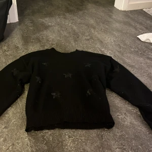 Svart stickad tröja med paljettstjärnor - Svart stickad tröja från Gina Tricot med snygga paljettstjärnor framtill. Tröjan har rund hals, ribbade muddar och lång ärm. Perfekt för dig som gillar en enkel men ändå glittrig look. Har inte använt så många ggr men har tvättat den mer än vad jag har haft på mig den.❤️ storlek 146/152. är lite dålig på att ta bilder