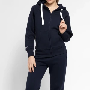 Mörkblå hoodie med dragkedja - Russemerch  mörkblå hoodie med vit snörning och huva. Tröjan har dragkedja framtill, två fickor och ribbade muddar vid ärmslut och nederkant. Perfekt för chill dagar och enkel att matcha med dina favoritjeans eller mjukisbyxor.