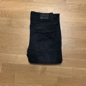 Nudie Jeans - Säljer ett par svarta Nudie Jeans Grim Tim i storlek 30/32. De har klassisk femficksdesign, raka ben och är tillverkade av 99% ekologisk bomull och 1% elastan för lite stretch. Snygga detaljer med Nudie-logga på bakfickan och mörk tvätt.