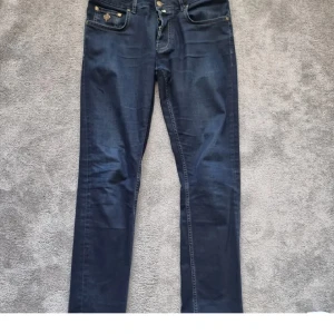 Morris Steve Satin Jeans mörkblå 30/32 - Mörkblå jeans från Morris, modell Steve Satin Jeans. Klassisk femficksdesign med snygga kontrastsömmar och broderad detalj på myntfickan. Tillverkade i 98% bomull och 2% elastan för en bekväm passform. Läderpatch med Morris-logga baktill.OBS! Reva bak, därav priset