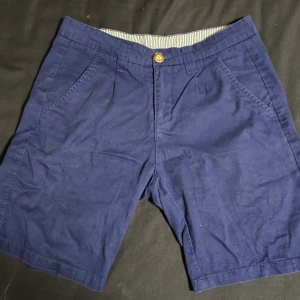 Mörkblå bomullsshorts med fickor - Snygga mörkblå shorts i bomull med klassisk passform. De har två sidofickor fram, två bakfickor med knapp och hällor för bälte. Perfekta för varma dagar och enkel att matcha med t-shirt eller skjorta.