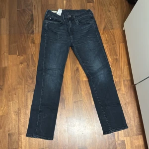 Levi's 511 mörkblå jeans - Snygga mörkblå Levi's 511 jeans med klassisk femficksdesign och raka ben. Jeansen har en diskret tvättad look och är tillverkade i mjukt denimtyg. Passar perfekt för dig som gillar en stilren och tidlös vibe.    L30