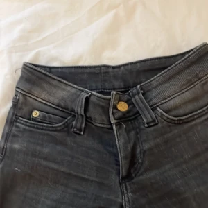 Svarta Cheap Monday jeans bootcut  fit - Svarta jeans från Cheap Monday med klassisk femficksdesign och guldiga nitar. Jeansen har en utsvängd passform och tydlig logga med dödskalle på bakfickan. Materialet är denim och färgen är tvättad svart för en cool look.