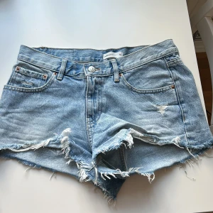 Ljusblåa jeansshorts från Gina Tricot - Säljer ett par ljusblå jeansshorts från Perfect Jeans med fransiga kanter och slitna detaljer framtill. Klassisk femficksmodell med knapp och dragkedja. Säljer då de är för stora. (Använt några fåtal gånger) 