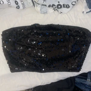 Svart paljett-tubtopp från SHEIN - Glittrig svart tubtopp från SHEIN täckt med svarta paljetter, de ser blått ut pga blixt🙏🏻💕