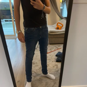 Blå jeans från Replay - Säljer ett par blå skinny jeans från Replay med klassisk femficksdesign och läderpatch bak i midjan. Jeansen har smal passform hela vägen ner och är tillverkade i stretchigt denim för extra komfort. Perfekta för dig som gillar en tajt look. Små fickor