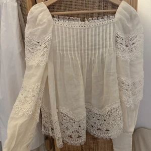 Blus & Other Stories  - Oanvänd Vit blus från & Other Stories i 100% ramie. Blusen har långa puffärmar, spetsdetaljer vid ärmslut och nederkant samt plisserad framsida. Nypris 1590 kr 