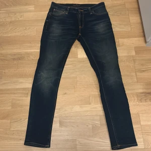 Nudie jeans - Mörkblå Skinny Lin jeans från Nudie Jeans i färgen Dark Double Indigo. Slimmad passform med skinny stil, klassiska fem fickor och snygga kontrastsömmar. Tillverkade av 99% ekologisk bomull och 1% elastan för extra stretch.