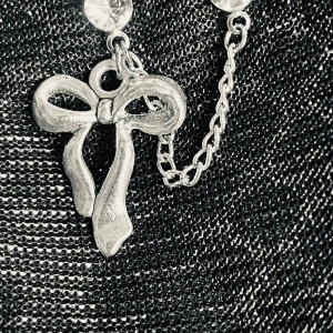 By prisförslag- 1 st Silverfärgat örhängen med rosett och diamanter  - Snyggt örhänge i silverfärg med glittrande stenar och en kedja som binder ihop två delar. Hängande rosett i metall ger en söt och trendig look. Perfekt för att lyfta din outfit med en unik detalj.