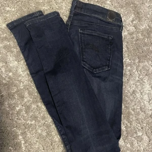 Mörkblå slimfit Replay jeans - Snygga mörkblå jeans från Replay med klassisk femficksdesign och diskreta detaljer. Jeansen har raka ben och slimfit passform. tillverkade i mjukt denimtyg med stretch för extra komfort. Perfekta för dig som gillar stilrena och tidlösa jeans.