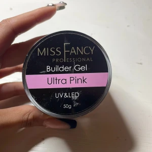 Miss Fancy Builder Gel Ultra Pink - Builder Gel Ultra Pink från Miss Fancy, 50g. En tjock, krämig gel i en snygg ljusrosa nyans, perfekt för att bygga och forma naglar. Passar både UV- och LED-lampa. Ger en jämn och glansig finish med en fräsch rosa ton.
