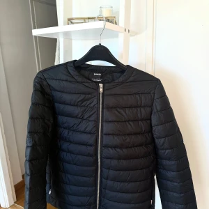 Svart jacka från mango XS - Svart snygg jacka från mango i storlek XS. Jackan har en quiltad design med raka sömmar, rund halsringning och en guld dragkedja framtill. Jackan är använd endast en gång då jag köpte fel storlek men kunde inte lämna tillbaka. Jackan är väldigt lätt💗