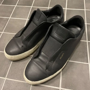 Svarta sneakers från Axel Arigato - Svart snygga Arigato skor. Skorna är använd smycket som man kan se på sista bilden. Även på sulan ser man att de är använda då det är lite smutsiga. Skorna är inte sönder någon stans.