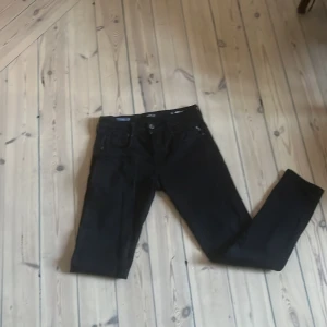 Svarta replay anbass jeans  - Svarta replay anbass jeans med klassisk femficksdesign och smal passform. Jeansen är tillverkade i ett stretchigt bomullsmaterial och har svarta sömmar och detaljer. Perfekta för dig som gillar en stilren och enkel look.