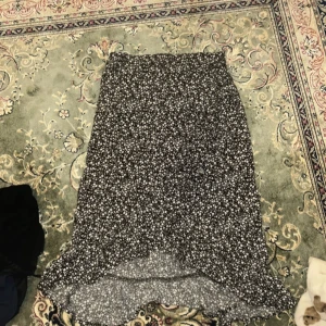 Svartvit blommig kjol från Ü - Svartvit långkjol från kapgal med småblommigt mönster. Kjolen har en lätt utsvängd form och resår i midjan för skön passform. Perfekt för dig som gillar en stilren men ändå söt look.