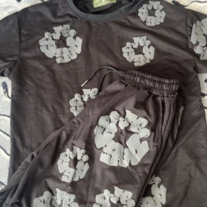 Svart t-shirt med grått mönster - Svart t-shirt från Advisory Board Crystals med unikt grått grafiskt mönster över hela plagget. Klassisk rund hals och korta ärmar. Tillverkad i mjuk bomull för en skön känsla. Perfekt för dig som gillar streetwear och vill sticka ut. Priset kan diskuteras 