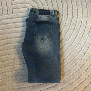 Jacob cohen jeans - Snygga blå jeans från Jacob Cohen med klassisk femficksdesign och ljusa slitningar framtill och baktill. Jeansen har normal passform och raka ben, tillverkade i mjukt denimtyg med bälteshällor och knappstängning.