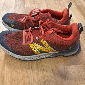 New Balance Fresh Foam trail sneakers - Säljer ett par New Balance Fresh Foam trail sneakers i rött och gult med coola grafiska mönster och Vibram-sula. Skorna har snörning, mesh-ovandel och extra tåskydd. Perfekta för dig som gillar att sticka ut på löprundan eller i vardagen.