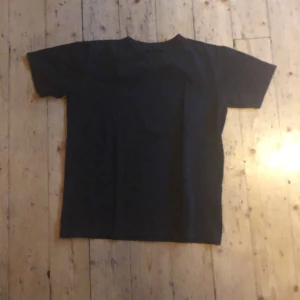 Svart basic t-shirt i bomull - Enkel svart t-shirt med rund hals och korta ärmar. Klassisk passform och tillverkad i mjuk bomull, perfekt till jeans eller shorts. Stilren och tidlös design utan tryck eller mönster.