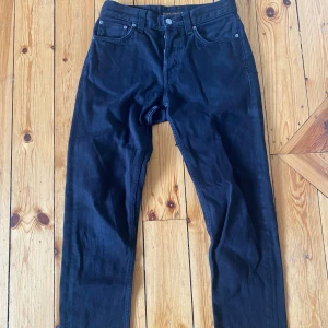 Nudie Jeans - Svarta jeans från Nudie Jeans med klassisk femficksdesign och raka ben. Jeansen har subtila sömdetaljer på bakfickorna och svart läderpatch i midjan. Tillverkade i slitstarkt bomullstyg med en stilren look som passar till det mesta.