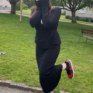 Svart  cardigan jacka från & kjol från Other Stories - Svart ribbad cardigan jacka från & kjol Other Stories med omlottknäppning och knytband i midjan. Långärmad och i mjukt stickat material, perfekt för lager-på-lager och chill vibes. Snygg v-ringning och smickrande passform. Den är stor på mig men stretchiga därför ser den fin ut på bilden 