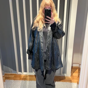 Svart pälsfodrad skinnjacka - Säljer en svart, längre jacka i skinn med mjukt pälsfoder och pälsdetaljer vid krage och ärmslut. Jackan har dragkedja framtill och två fickor med dragkedja. Oversized passform och riktigt mysig för kalla dagar. Står ingen storlek men gissar på XL/XXL. Köpt från beyond retro så fint men begagnat skick :)