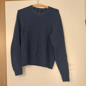 Blå stickad tröja från Uniqlo S - Mysig blå stickad tröja från Uniqlo i storlek S. Tröjan har rund halsringning, ribbade muddar och en klassisk, enkel design som passar perfekt till jeans eller kjol. Perfekt för kyliga dagar.