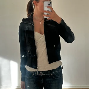 Vintage bomberjacka från Esprit - Svart bomberjacka från Esprit med ribbad krage och muddar. Jackan har dragkedja framtill, två fickor med knappar och en croppad passform.