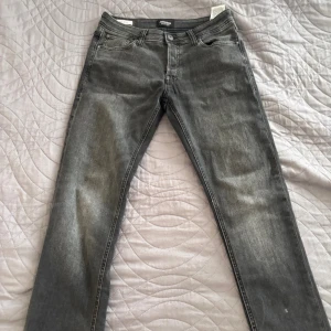 Grå jeansbyxor i slim fit, stl 30/32 - Snygga grå jeansbyxor i slim fit med klassisk femficksdesign och diskreta slitningar. Jeansen har normal midja och raka ben, perfekta för en stilren vardagslook. Tillverkade i mjukt bomullsmaterial med lite stretch för extra komfort.Har använt dem en gång.