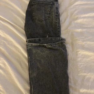 Gråa utsvängda jeans - Säljer ett par gråa jeans från Gina Tricot i storlek 32. Dem har bra skick men lite märke längs ner på byxorna.