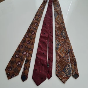 Tre snygga vintage slipsar i siden  - Säljer tre unika vintage slipsar: en brun blommig från GANT i Siden, en vinröd med prickigt/rutigt mönster från Enrico Cesare i 100% silke, och en brun/grå mönstrad från Cerruti 1881 i silke. Perfekt för dig som vill sticka ut med coola detaljer och klassiska märken.
